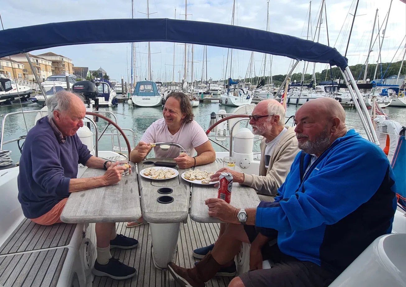 Sailors chatting around the cockpit table of a yacht in a marina