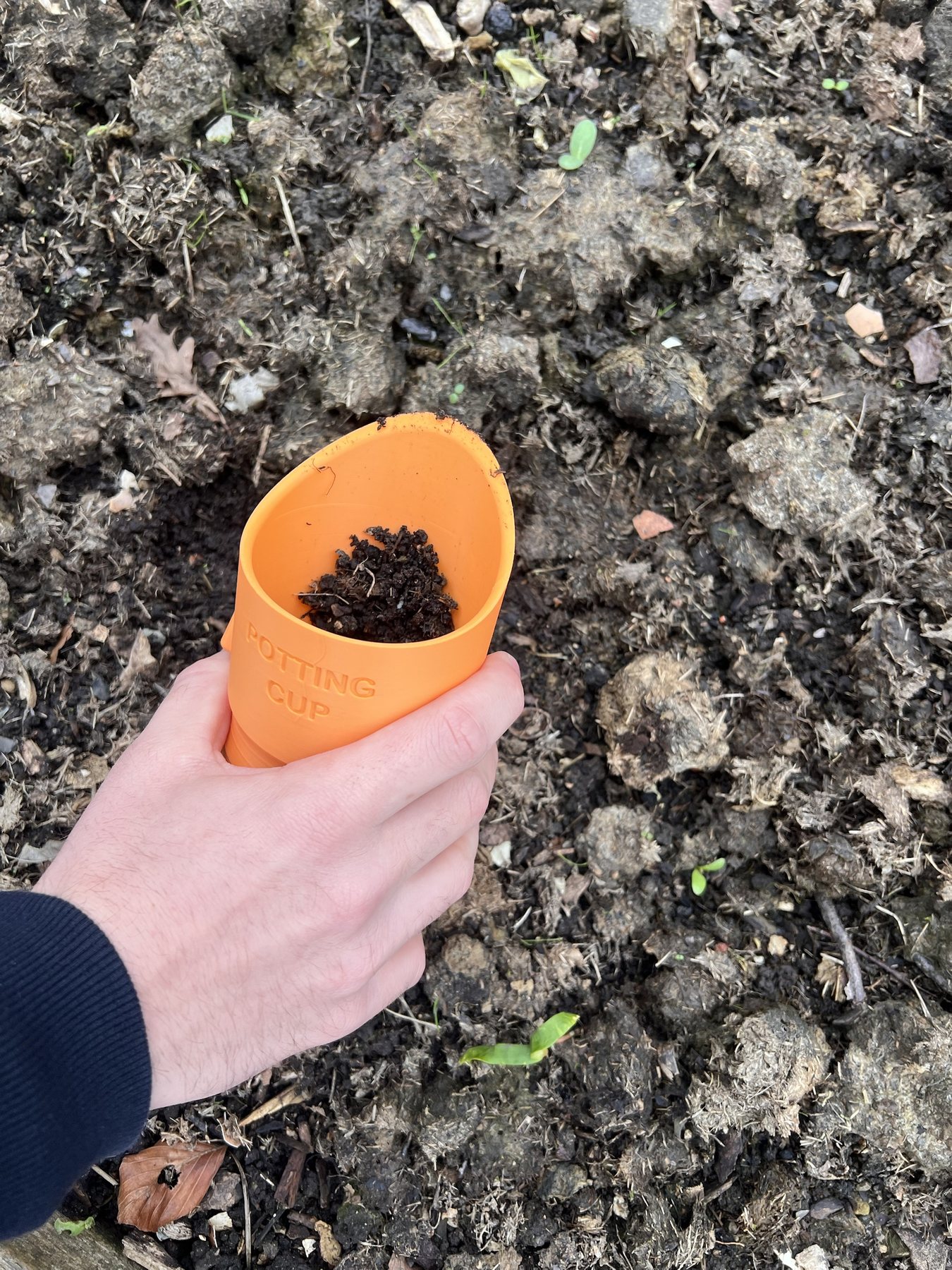 Scooping soil from a raised bed with the Potting Cup